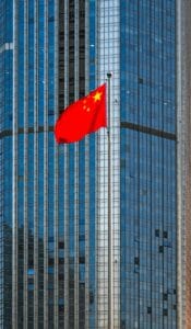 pexels-photo-30011537-30011537 Chinese national flag waving in front of a modern skyscraper, symbolizing urban progress.